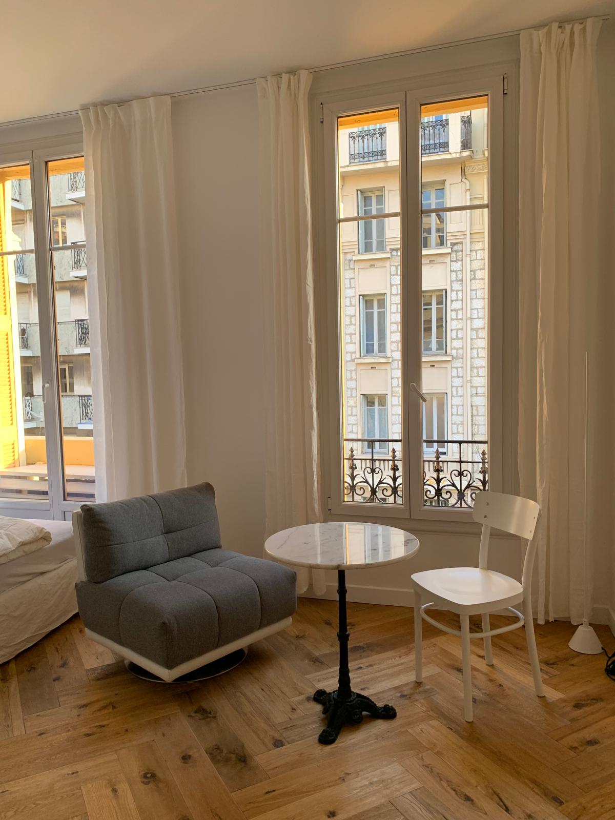 Fauteuil, table de bistrot en marbre et balconnet donnant sur les façades niçoises