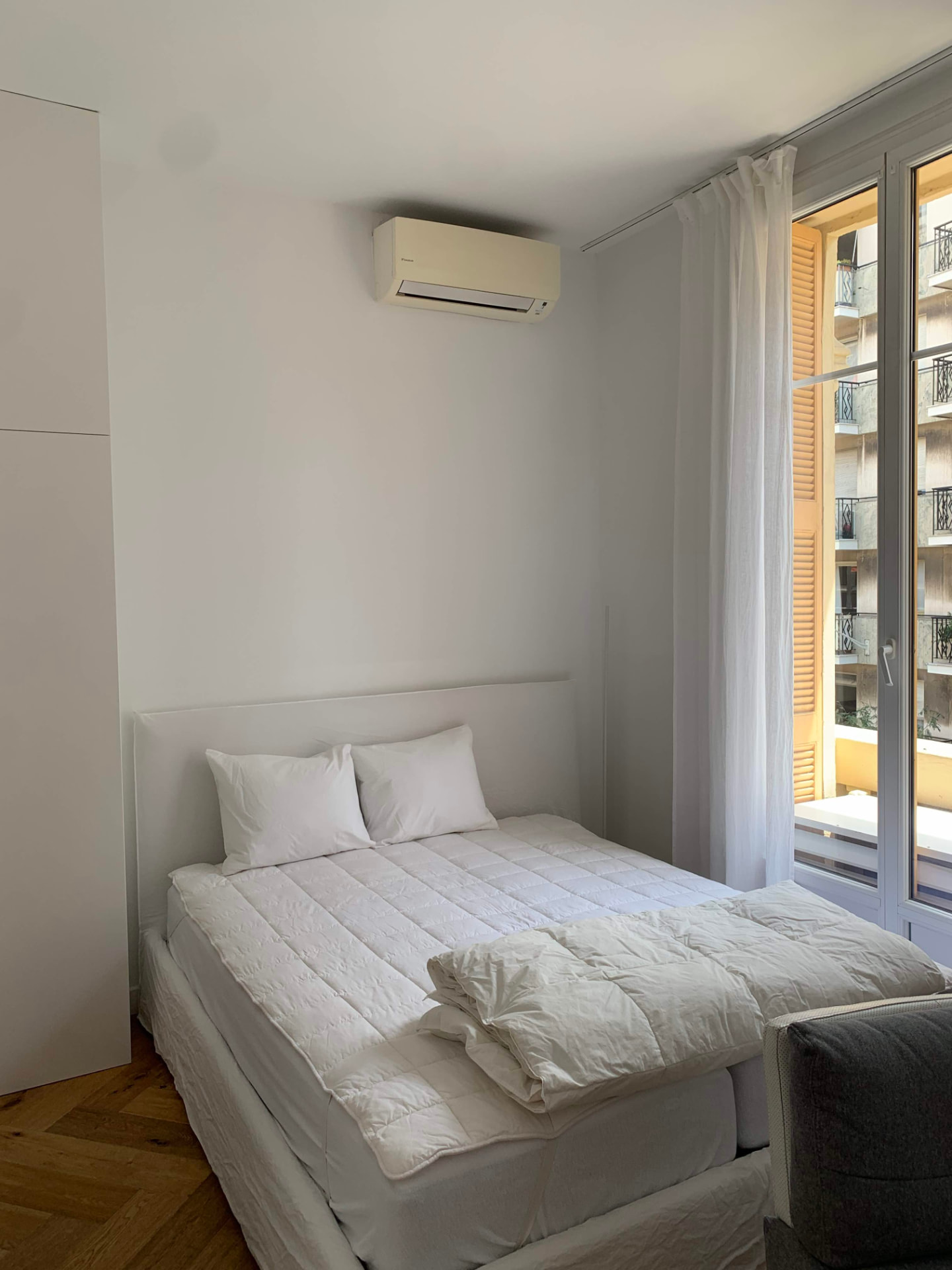 Lit double avec linge blanc, placards intégrés et climatisation murale