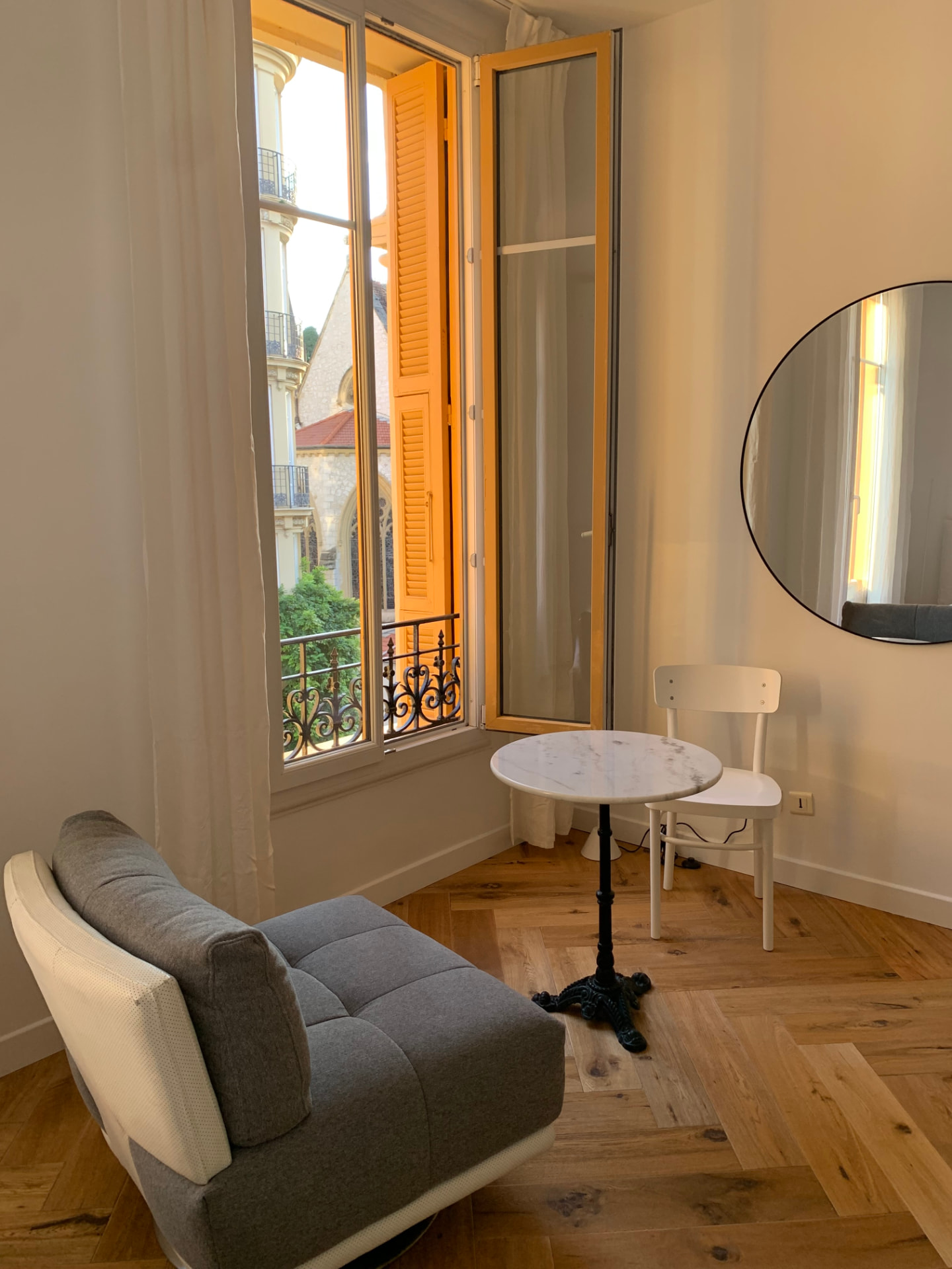 Fauteuil pivotant et table de bistrot en marbre près des fenêtres à la française ouvertes avec vue sur l'église