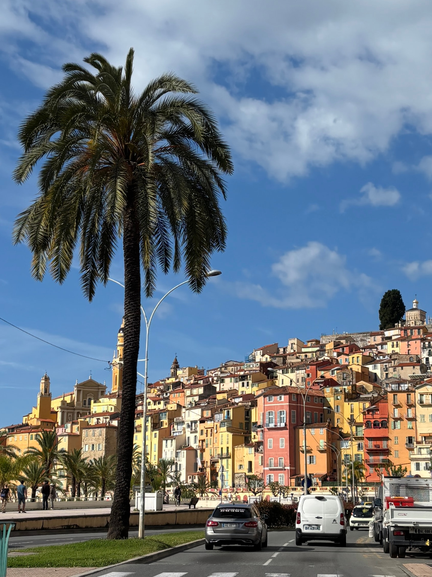 La vieille ville colorée de Menton dominant le front de mer, encadrée par un grand palmier