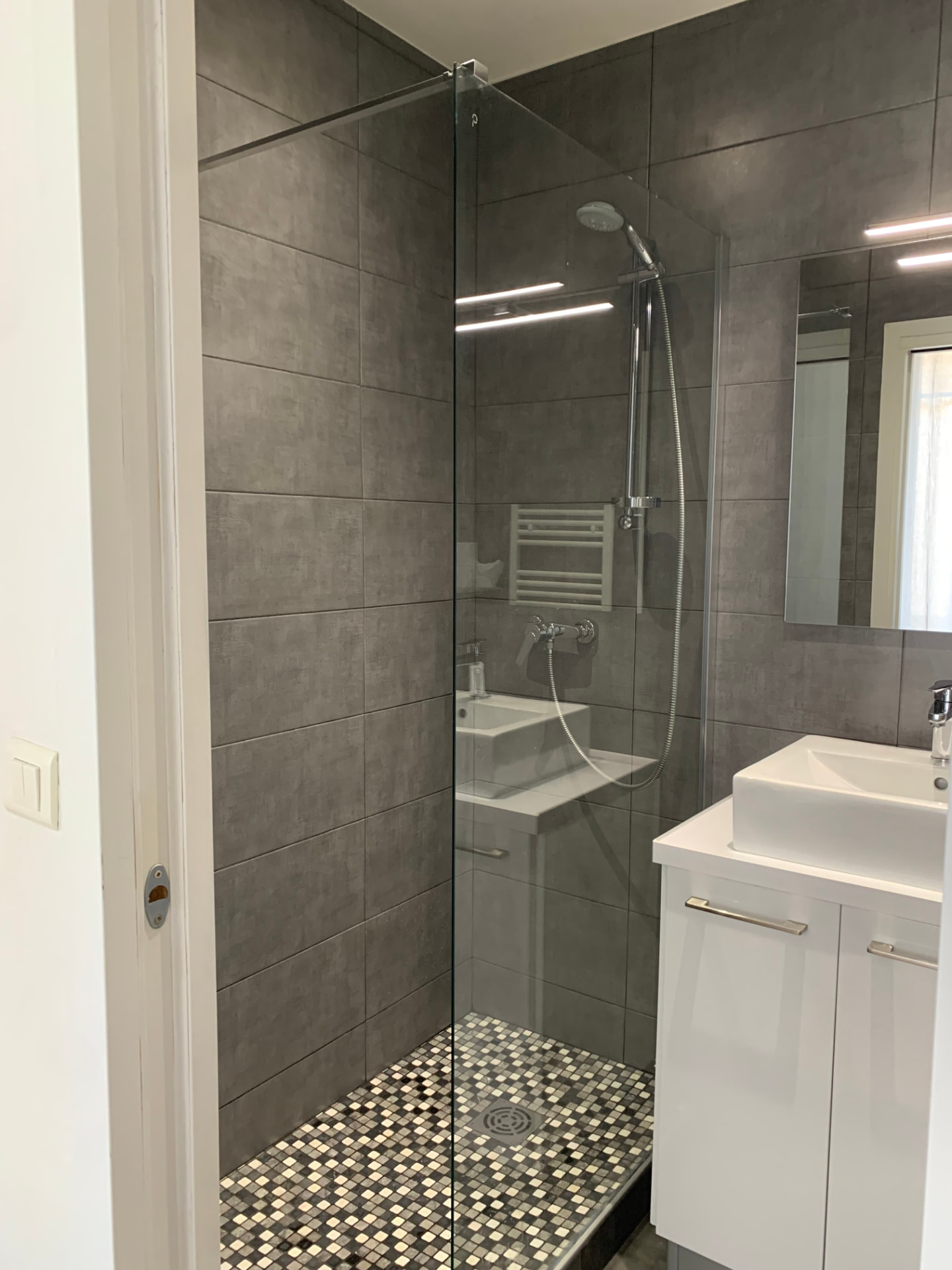 Douche à l'italienne vitrée sur sol en mosaïque près d'une vasque design