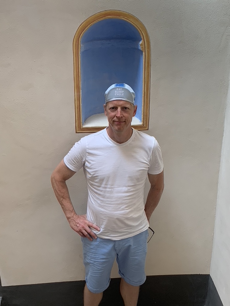 Jean, een van uw gastheren, voor een crèmekleurige muur met een blauwgeschilderde nis bij het Hôtel du Couvent in Nice